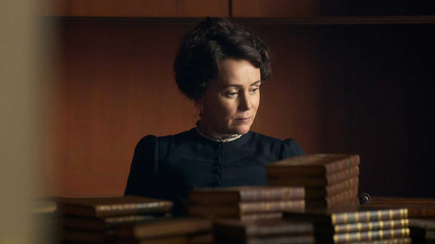 A woman sits surrounded by books in PBS Masterpiece's Miss Austen.