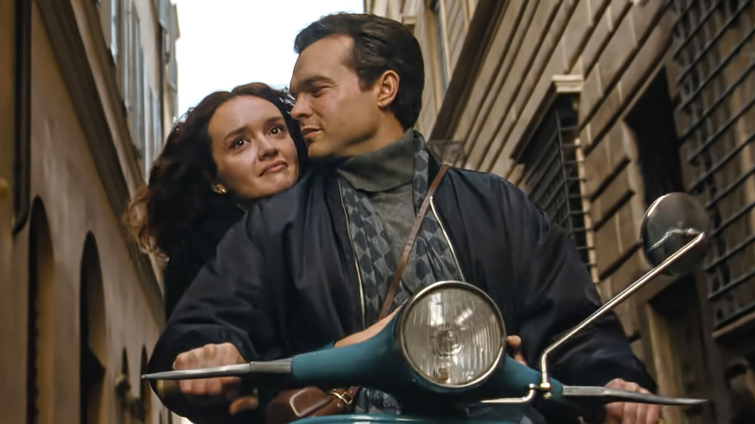 Olivia Cooke holding onto Alden Ehrenreich as he rides a motorcycle in A Talent for Murder