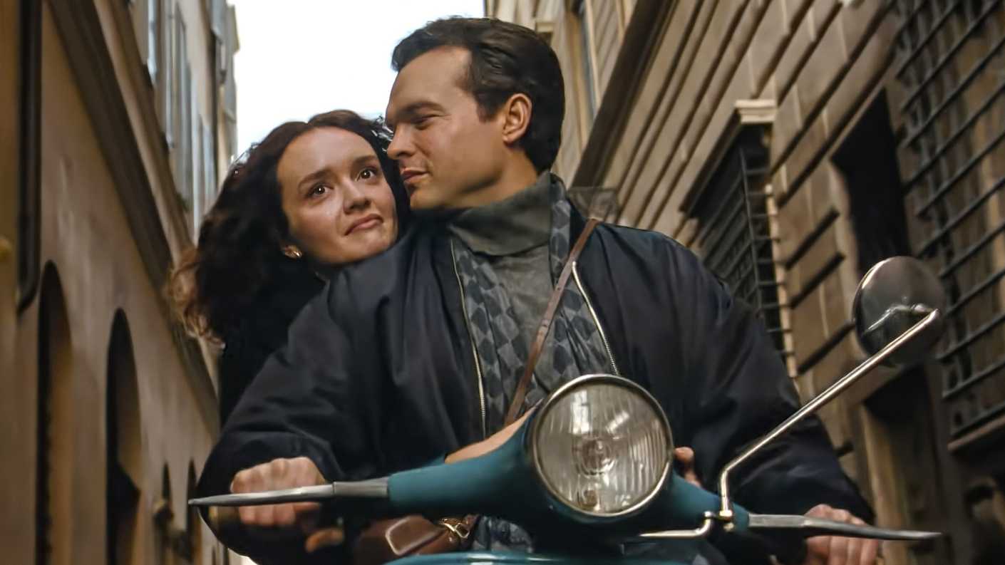 Olivia Cooke holding onto Alden Ehrenreich as he rides a motorcycle in A Talent for Murder