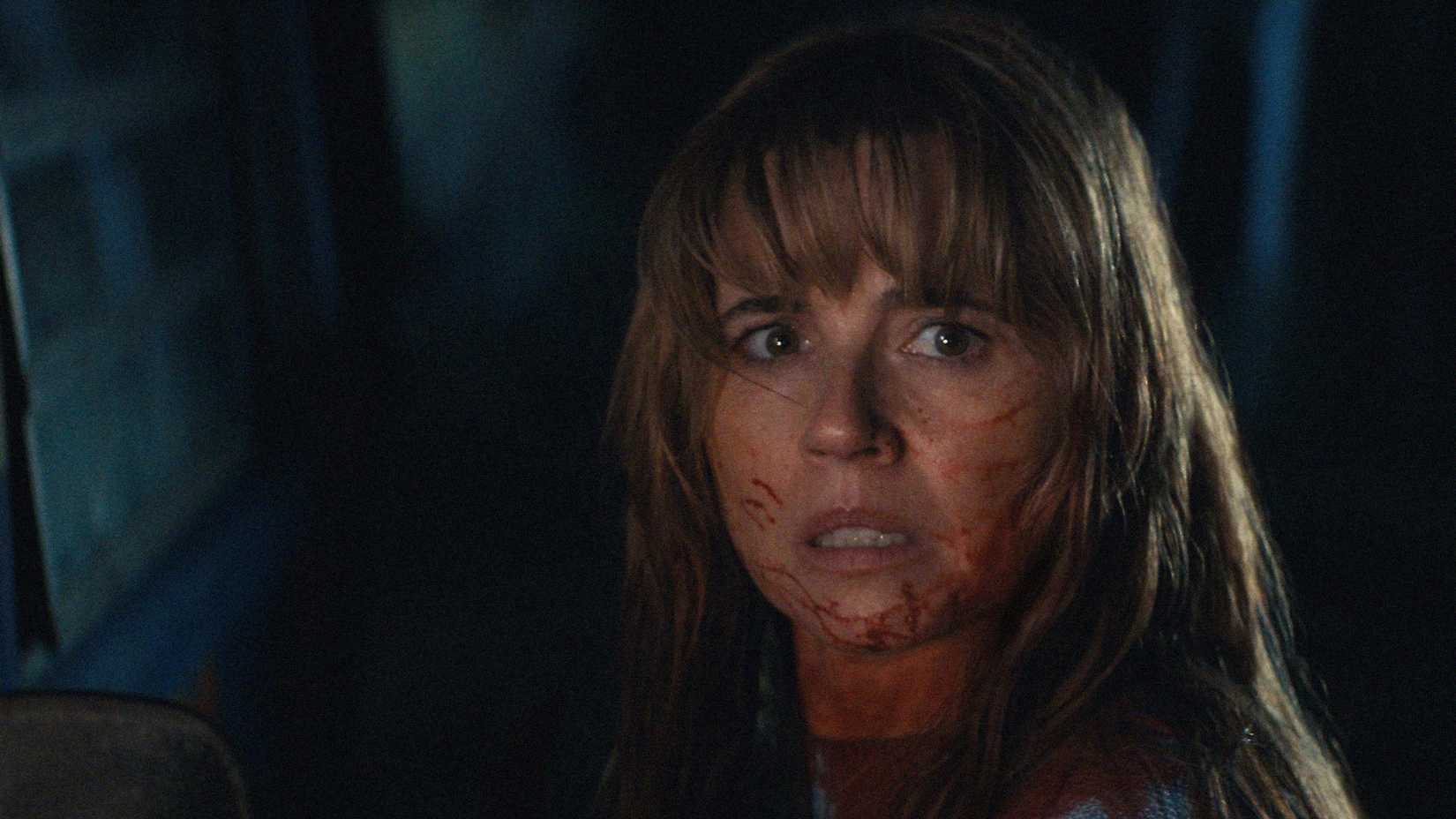 Pamela Voorhees' face is covered in blood and she looks shocked in Crystal Lake