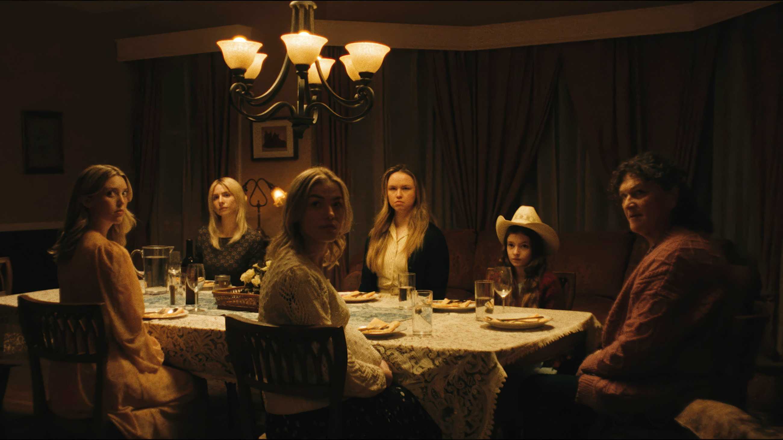 Patti and her daughters seated at the dinner table and looking toward camera in Breeder