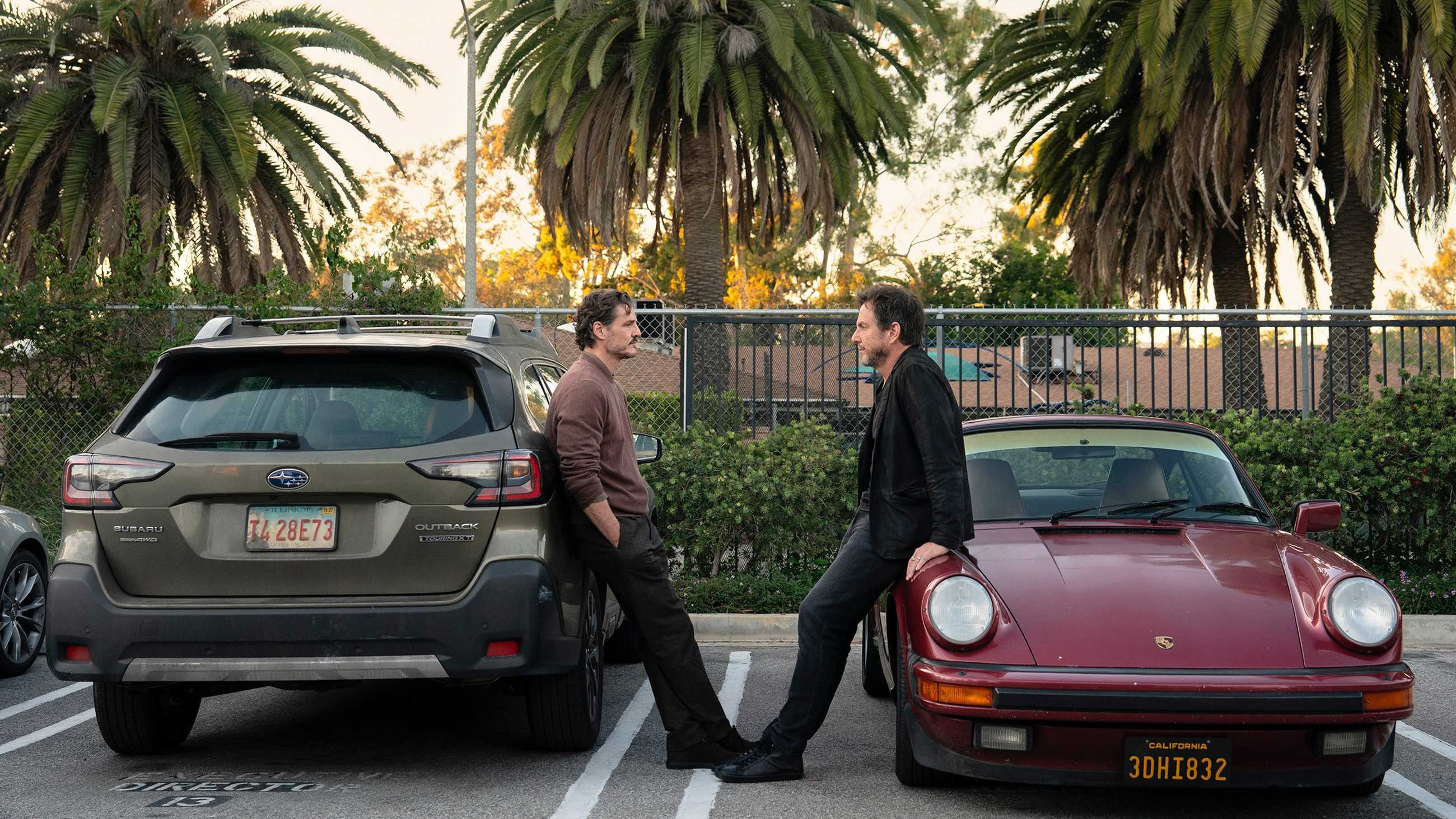 Pedro Pascal and Will Arnett leaning on cars facing each other in Behemoth!