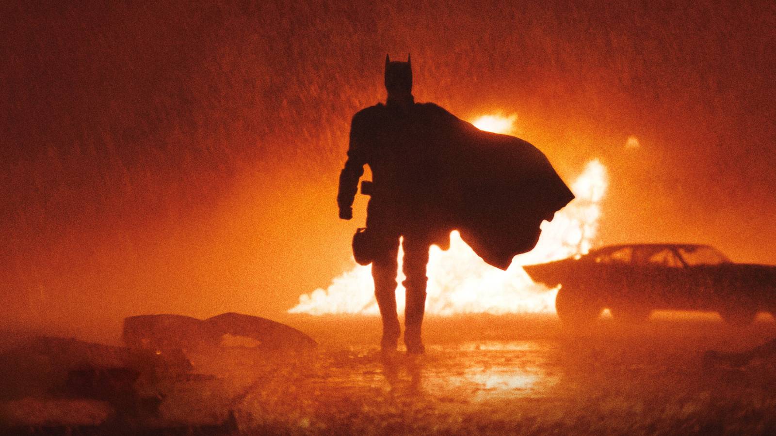 Robert Pattinson walking away from the Batmobile in costume in The Batman