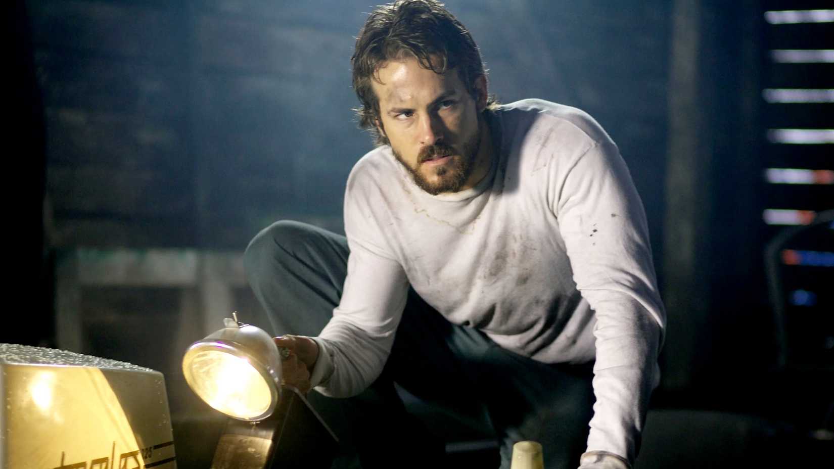 Ryan Reynolds as George Lutz holding a torch in The Amityville Haunting remake