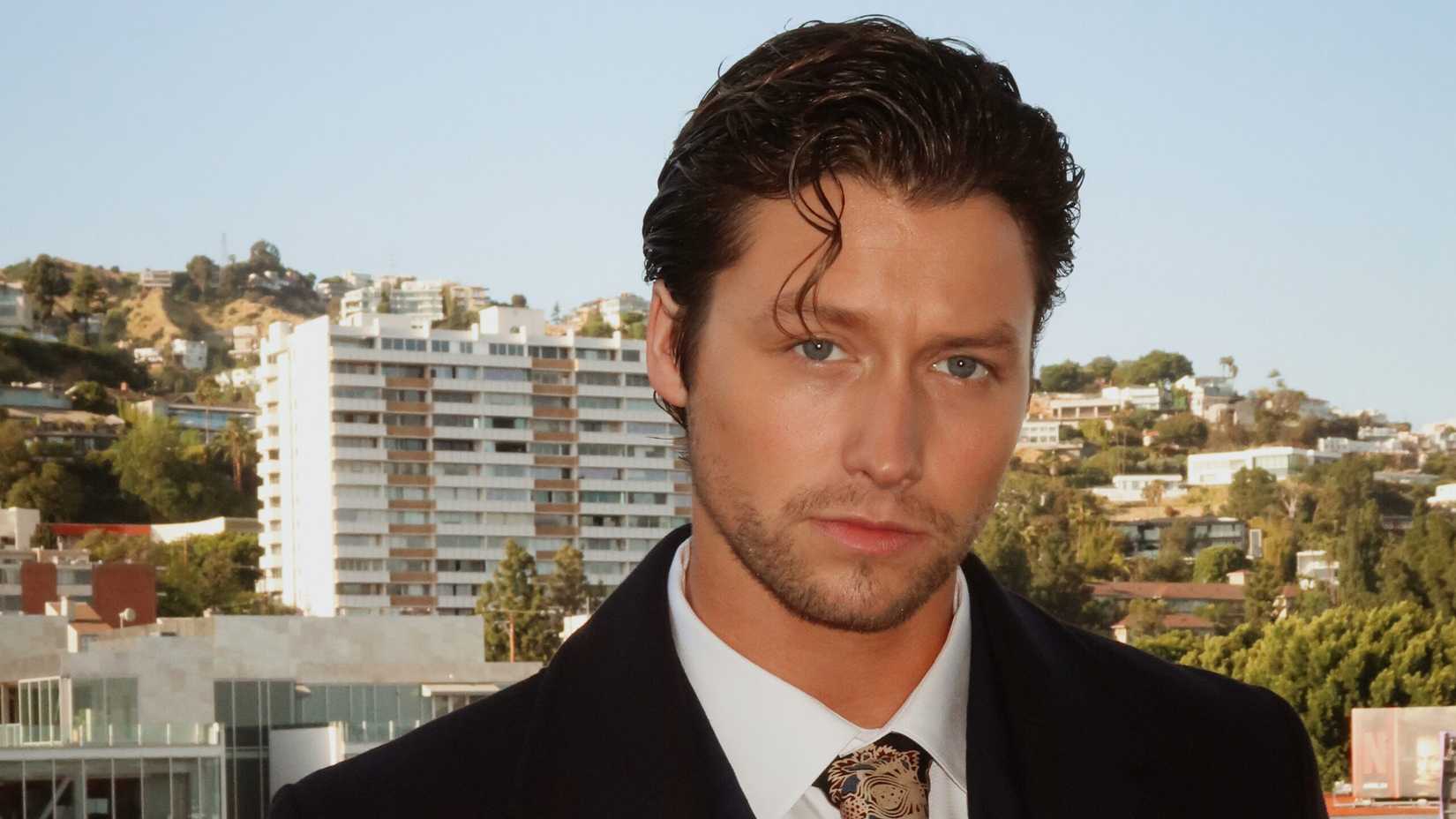 Stephen Kalyn posing on a balcony in front of high rise buildings.