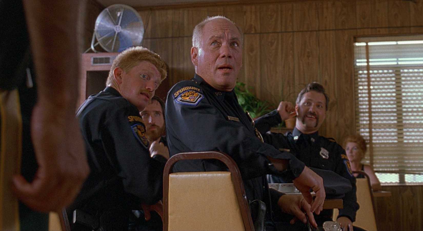 Daniel von Bargen and three other actors wearing police uniforms look shocked at someone off-screen in Super Troopers. 