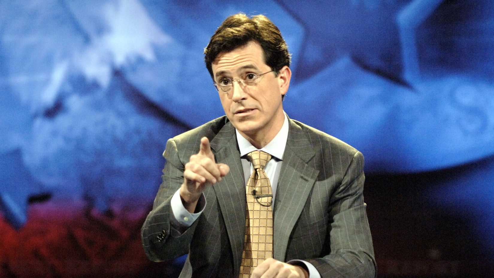 THE COLBERT REPORT, Stephen Colbert at his desk pointing (Season 1, 2005).