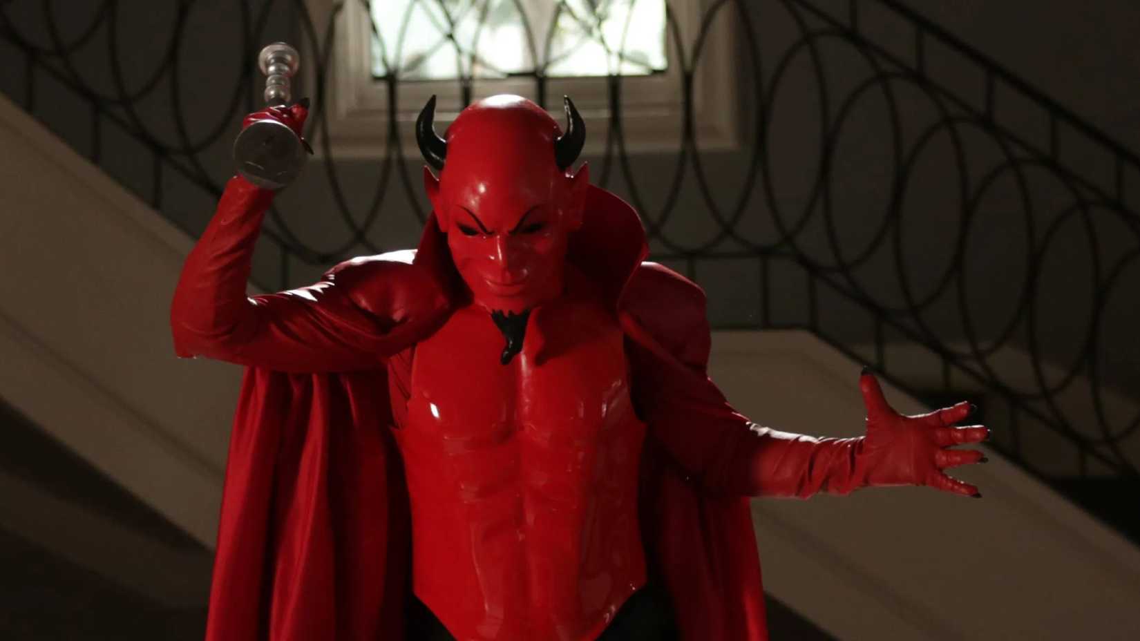 The red devil holds a trophy as a weapon in Scream Queens