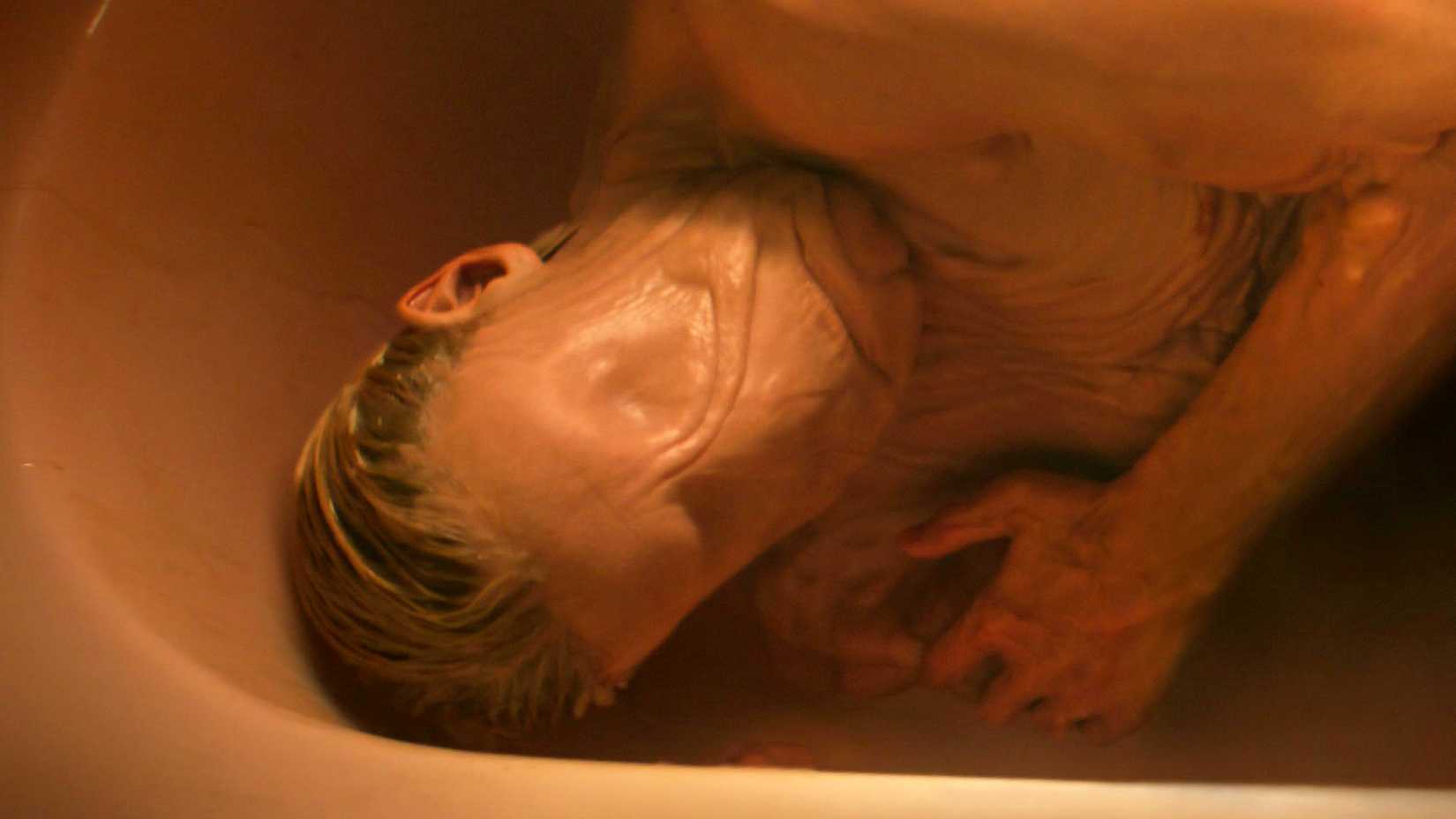Tom Rhys Harries as Matt Hagen lying in a tub with his skin smoothed out in Clayface