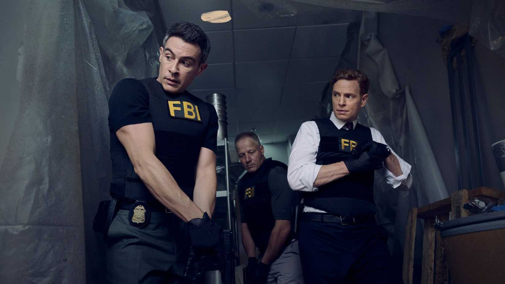 Three men wearing FBI vests and holding weapons are about to conduct a raid
