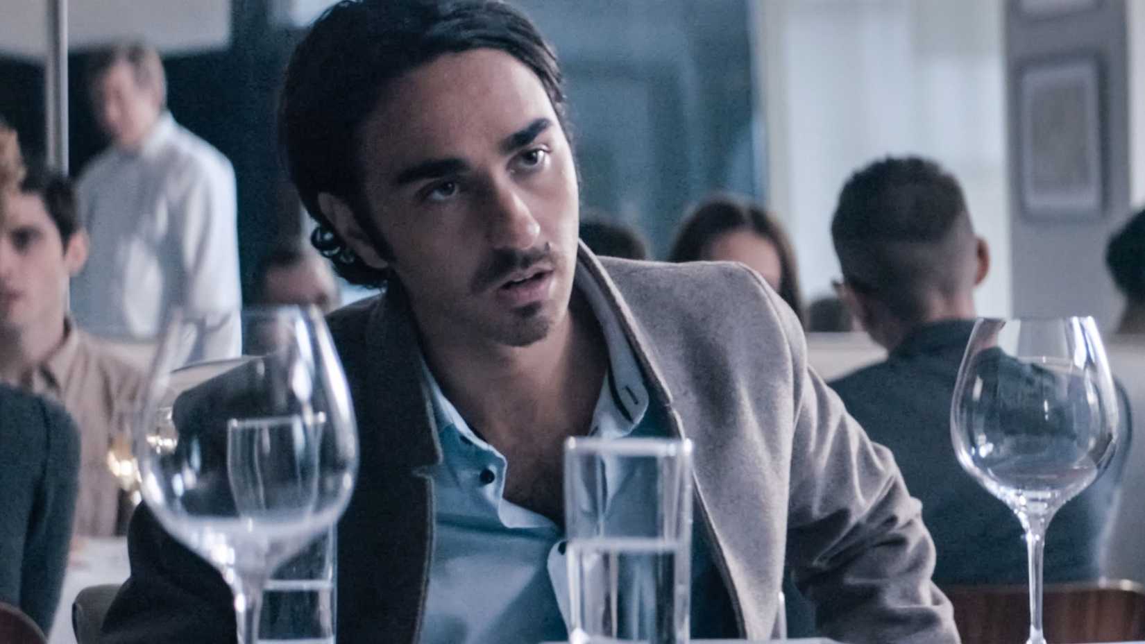 Alex Wolff sitting at a table in Pig