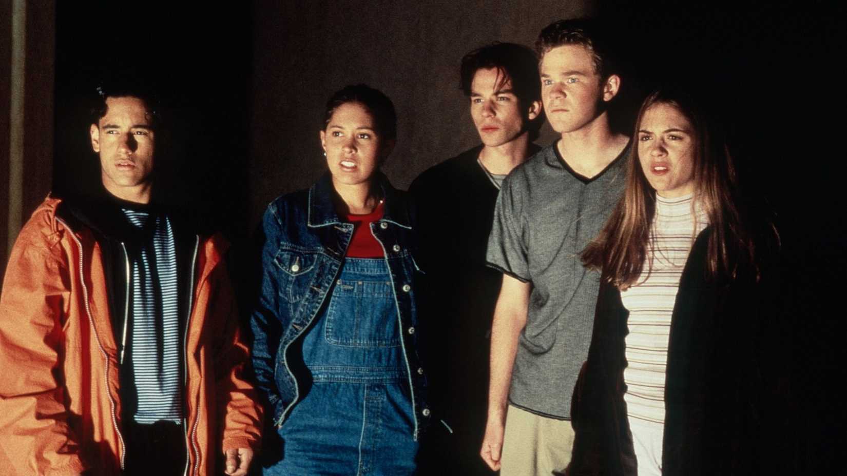 A group of teenagers stands around looking quizzically at something