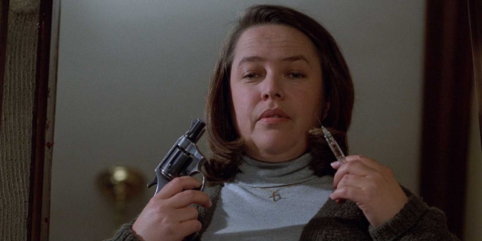 Kathy Bates holding a gun and a syringe in Misery.