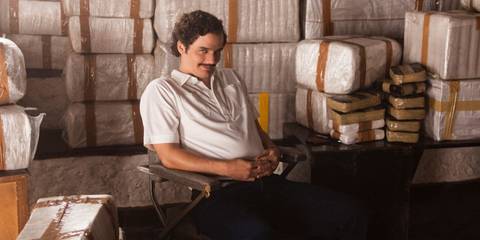 Wagner Moura as Pablo Escobar sits in the middle of several cocaine shipments in Narcos.