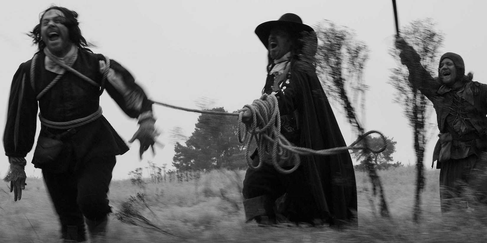 bewitched ritual practice in A Field in England, a feral character is held by a rope as the others charge behind him